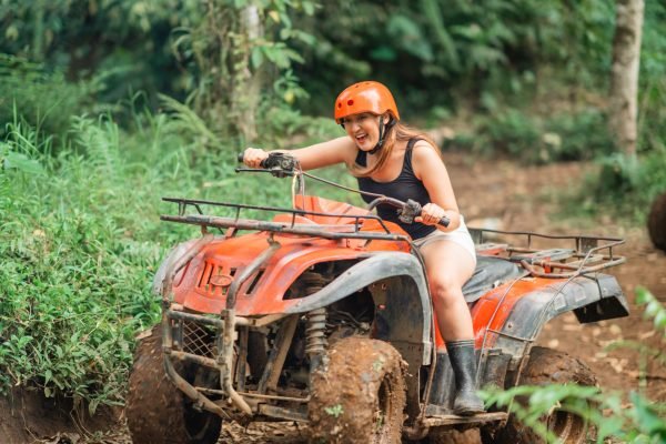 excited asian woman screaming while riding the atv through the difficult way at atv arena
