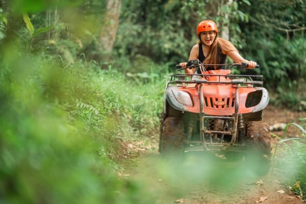 beautiful asian woman riding the atv happily through the atv arena spending her holiday